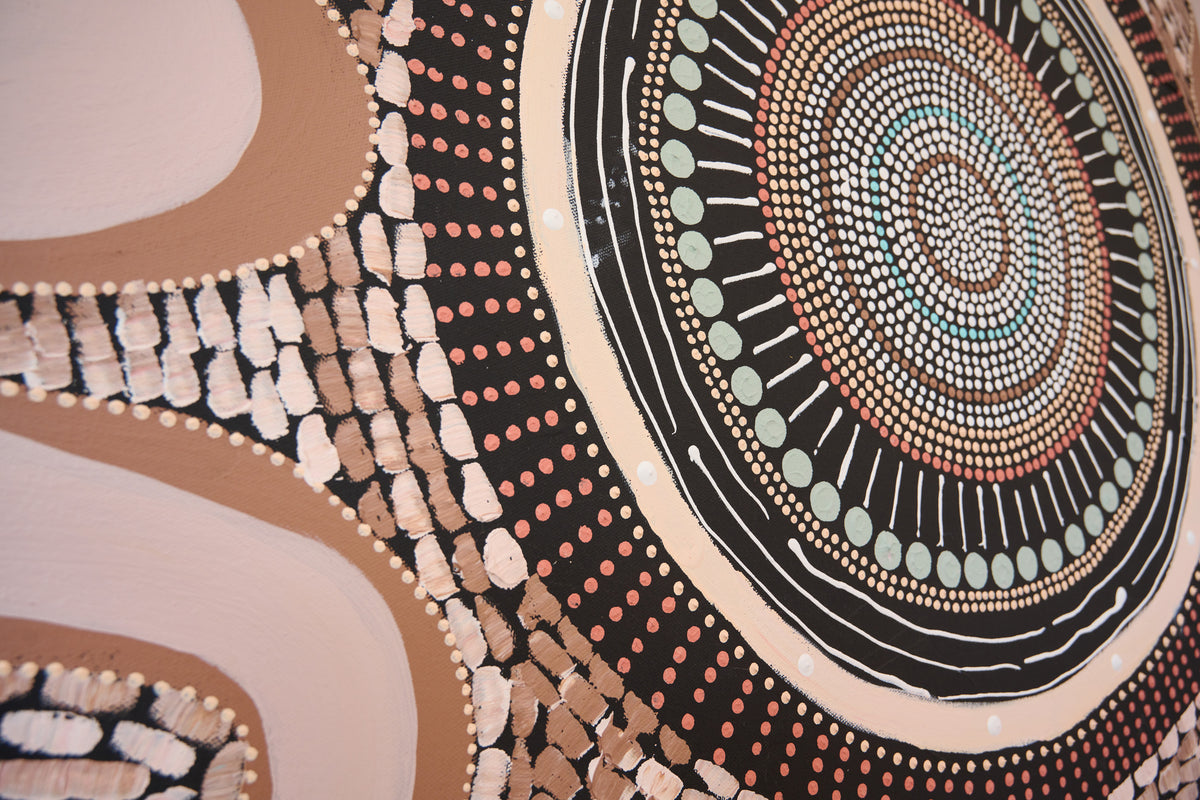 Close-up of a circular Aboriginal-style dot painting with concentric circles, black bands, tan and brown textured marks, and small turquoise and pale green dots on a light background.