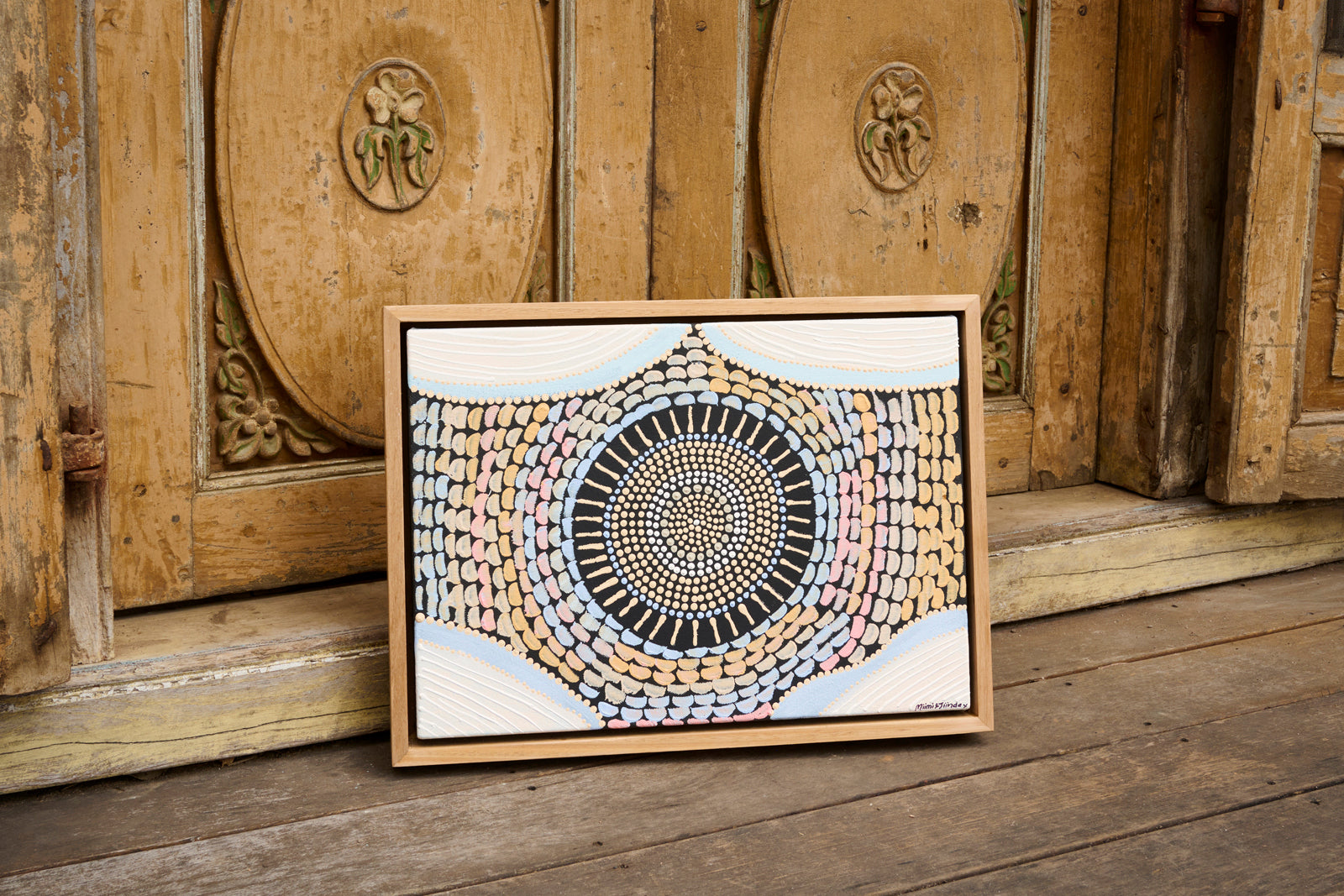 Framed abstract artwork on a wooden floor with a wooden panel background
