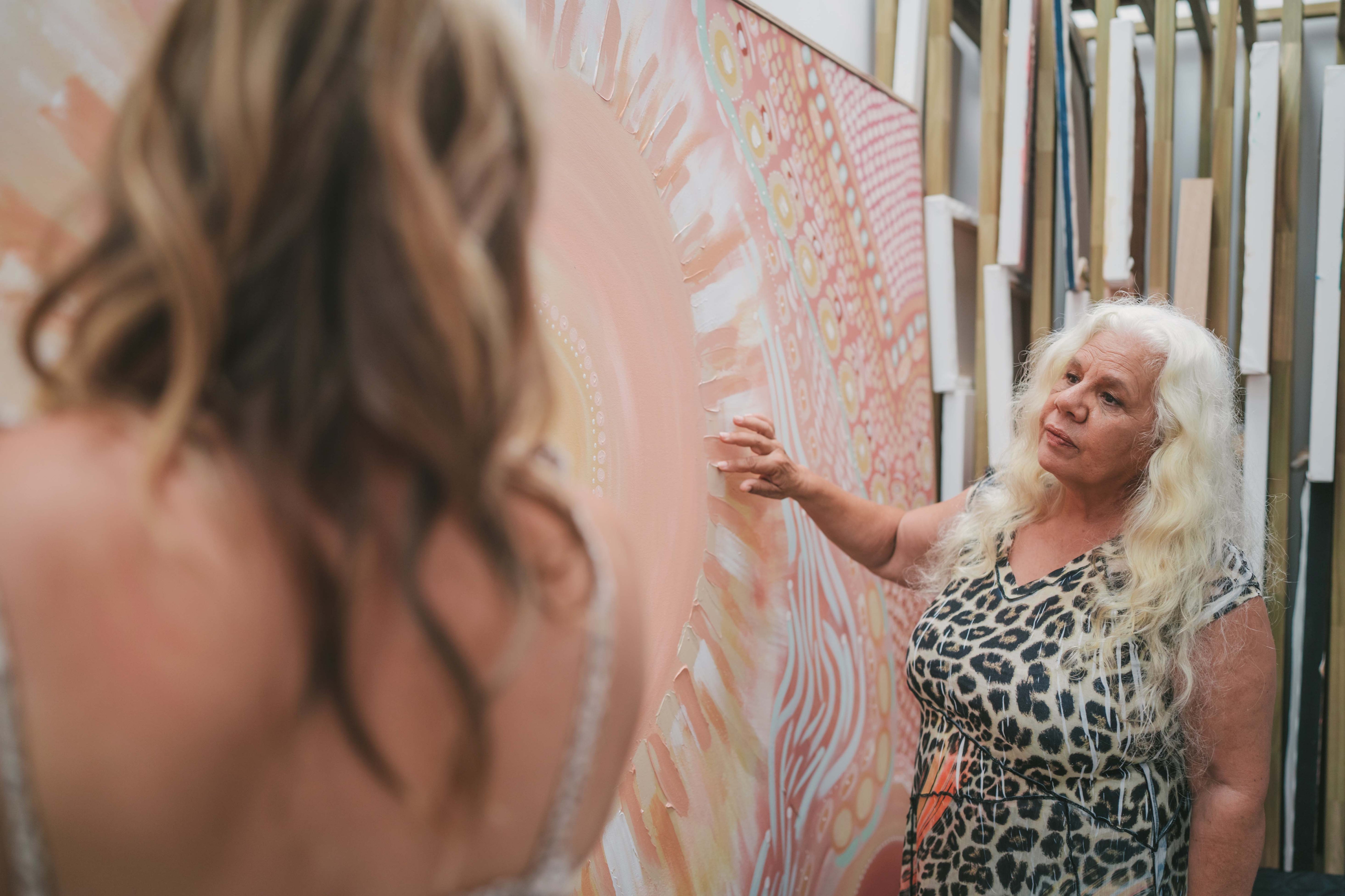 Woman in a leopard print dress pointing at a colorful abstract painting
