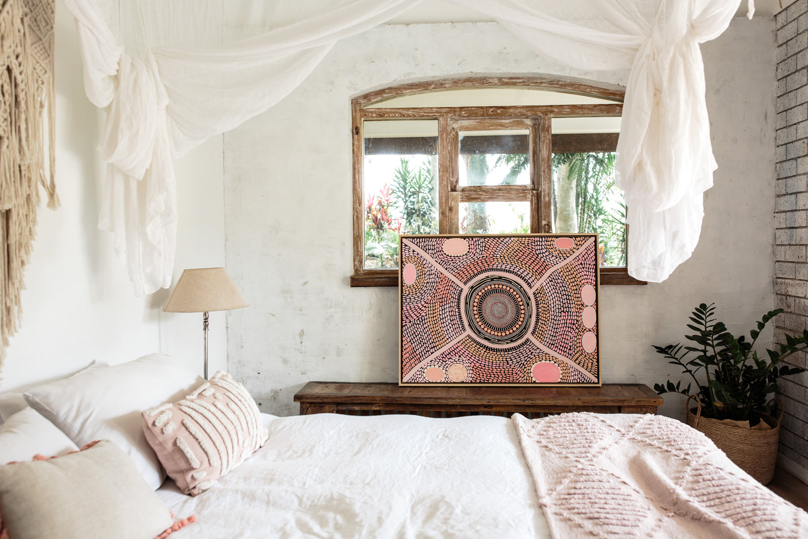 Bohemian bedroom with a bed, mirror, and decorative wall art.