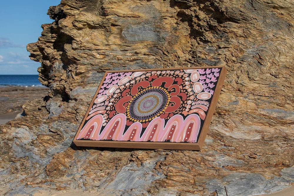 Decorative mandala art piece on a rocky surface by the beach