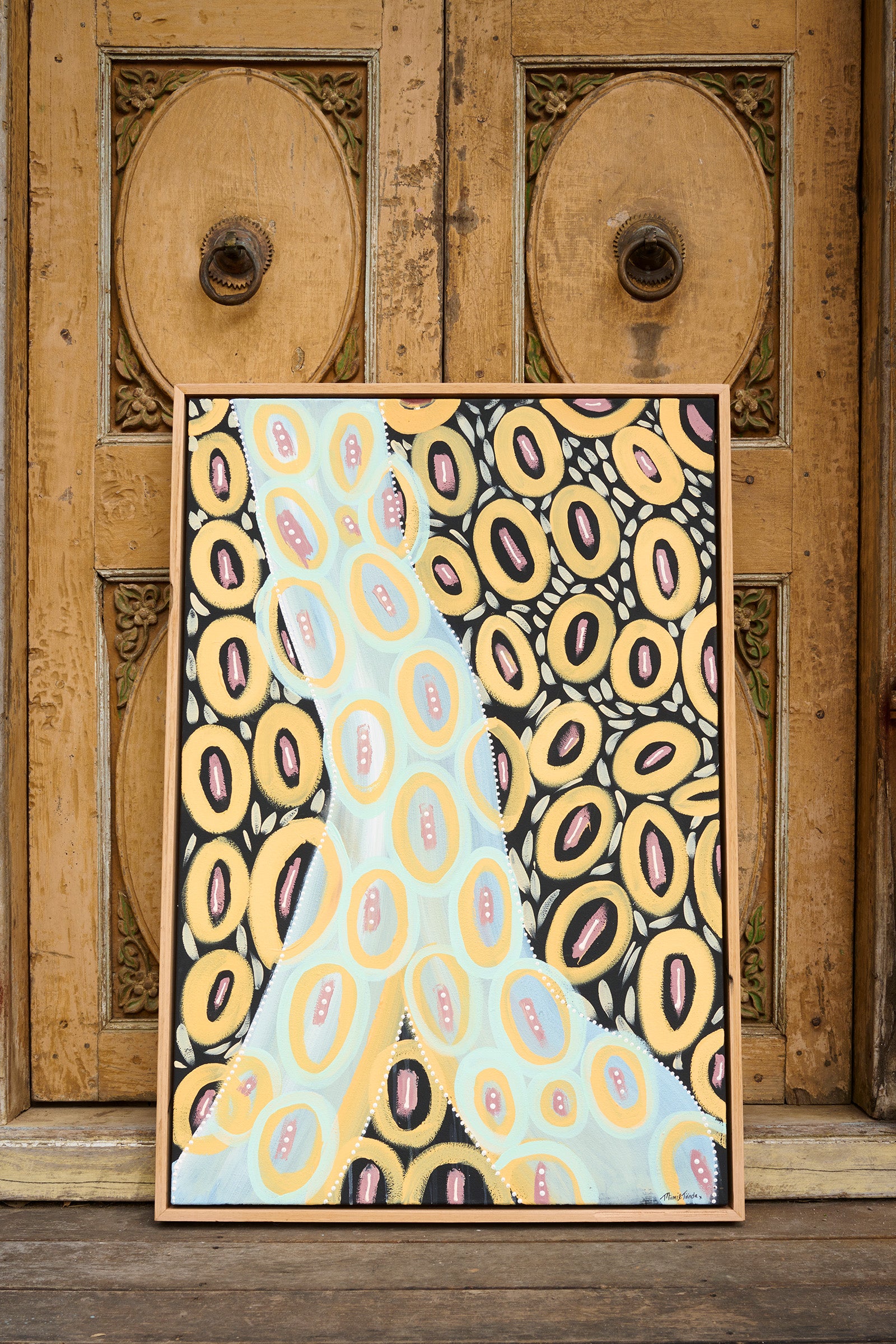 Abstract art print with yellow and blue pattern on a wooden door background