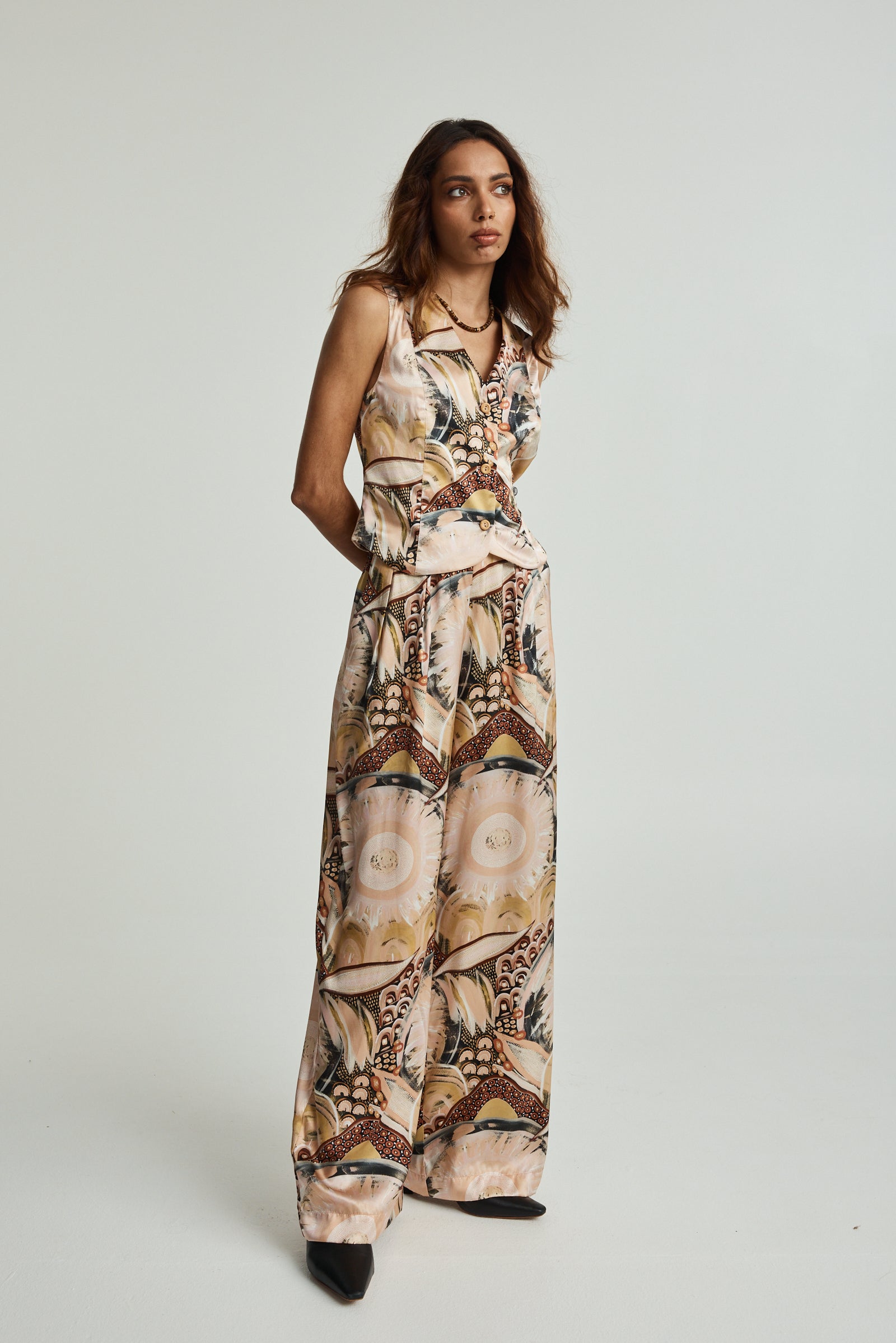 Woman wearing a patterned jumpsuit on a plain background