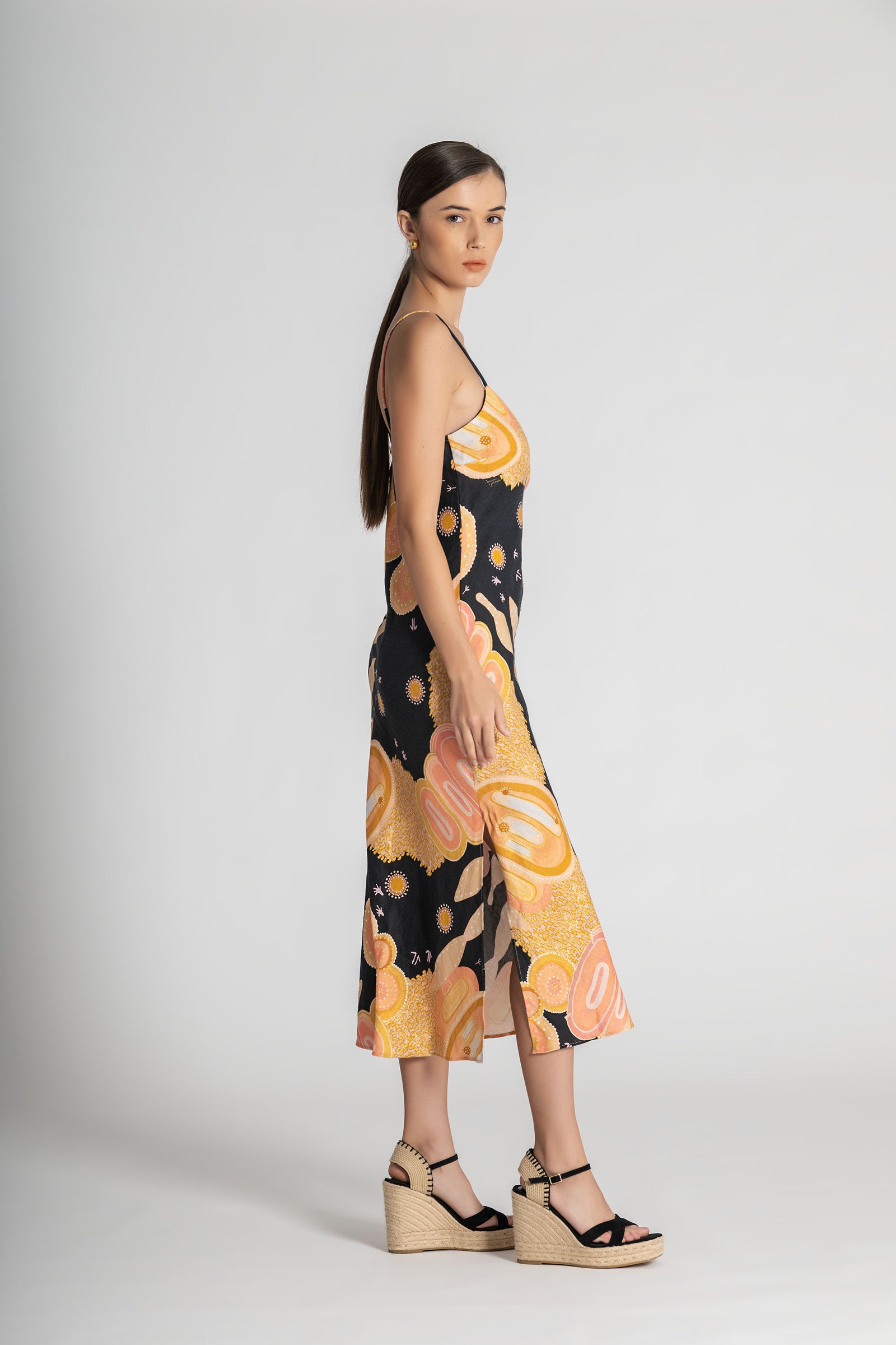 Woman wearing a sleeveless dress with a black and yellow abstract pattern on a white background